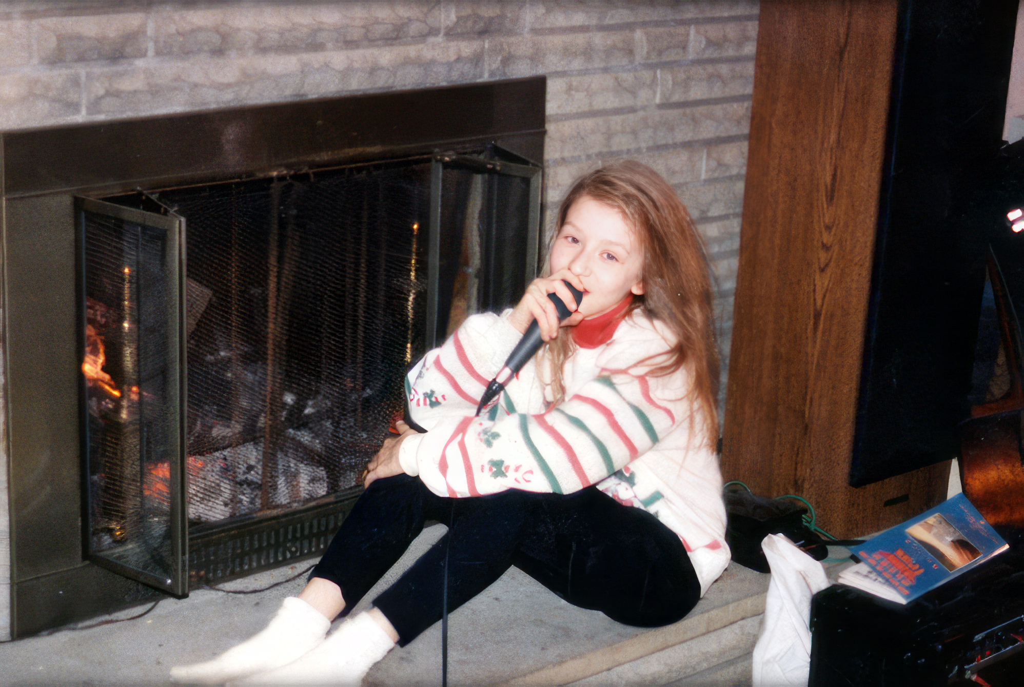 Christina keeping warm by the fireplace, singing.
